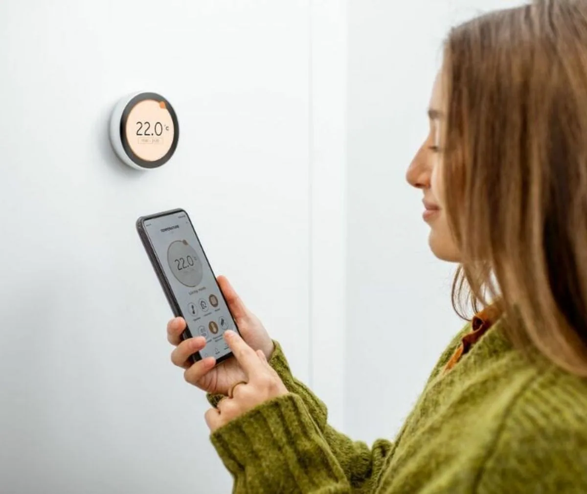 Woman adjusting a smart thermostat using a phone app