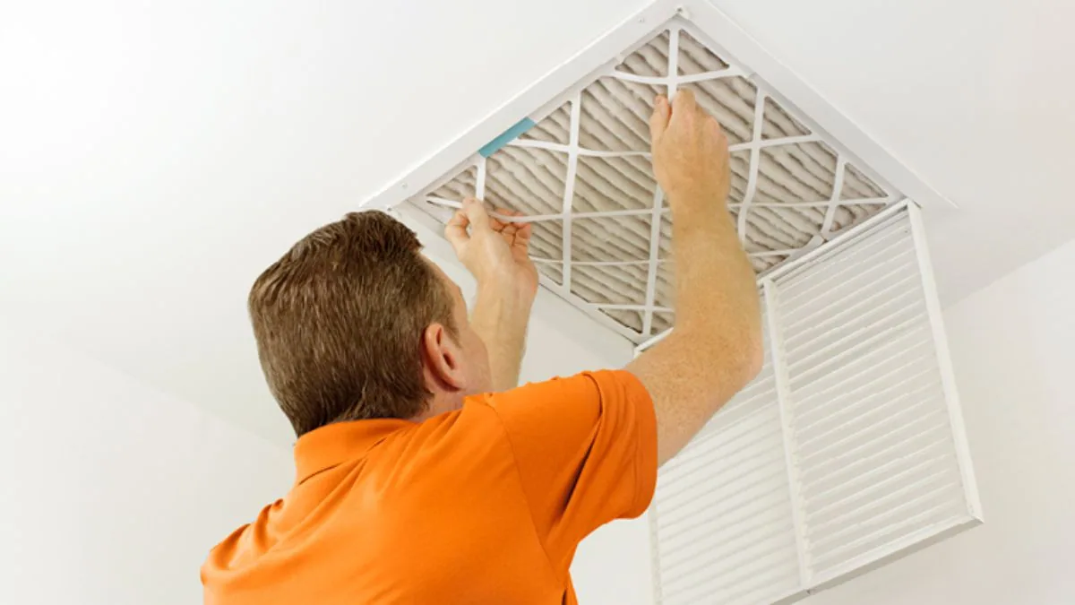 Man replacing a pleated air filter in a ceiling return vent