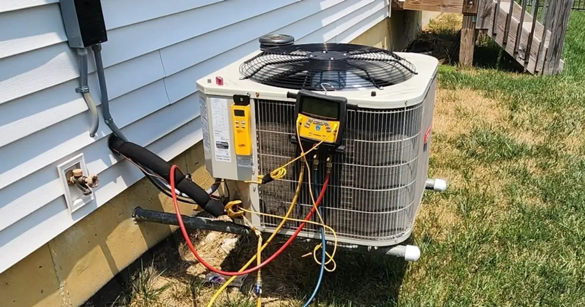 Refrigerant gauges connected to an outdoor air conditioner beside a house during service