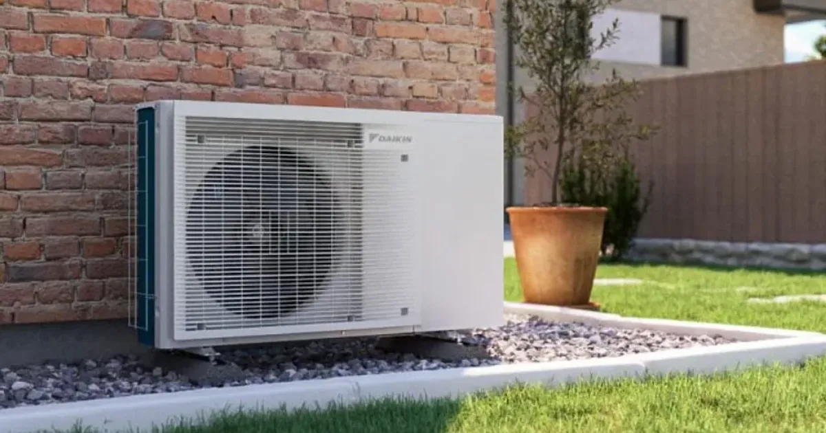 Outdoor heat pump unit beside a brick wall