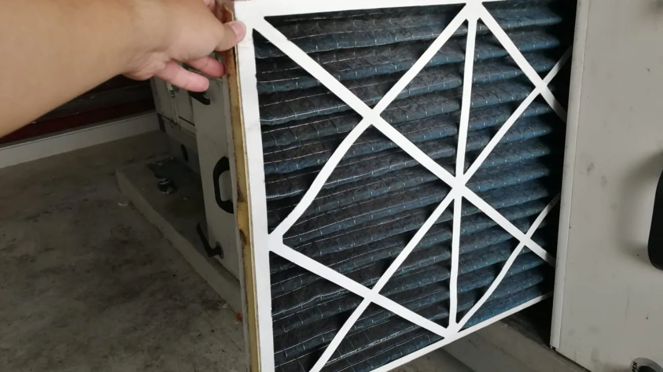 Hand replacing a pleated furnace filter in a home HVAC system