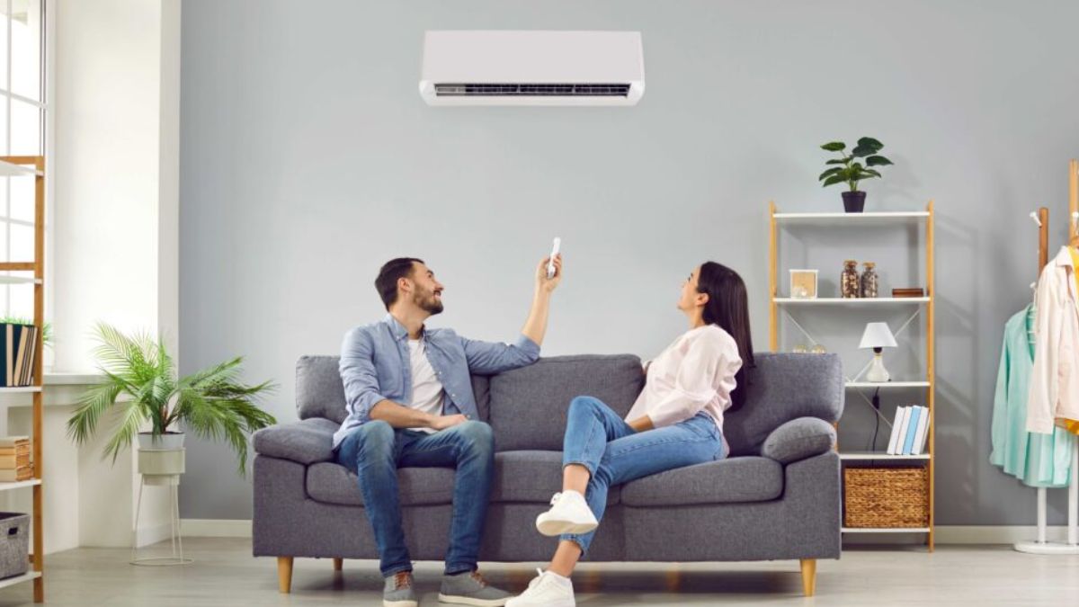 Couple on a couch using a remote for a wall-mounted air conditioner