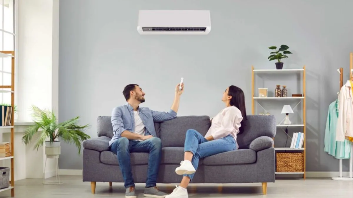 Couple on a couch using a remote for a wall-mounted air conditioner