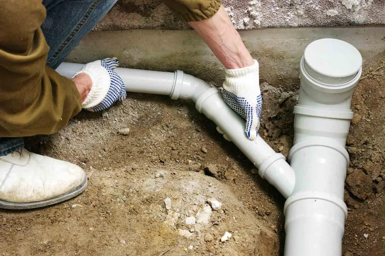 Plumber installing PVC sewer pipe and a main drain cleanout