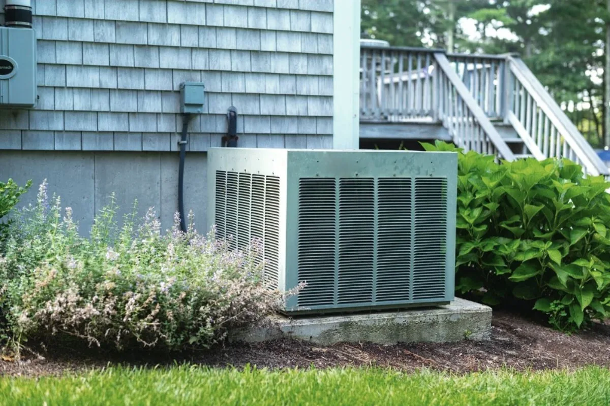 Outdoor air conditioner unit beside a home with landscaping