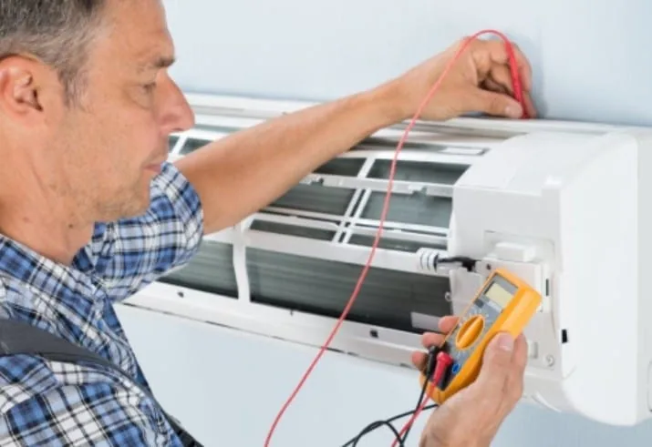 HVAC technician testing an air conditioner with a multimeter