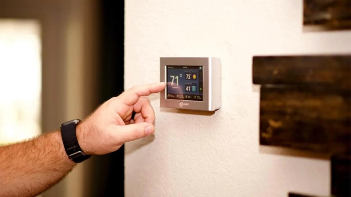 Homeowner adjusting a smart thermostat mounted on the wall
