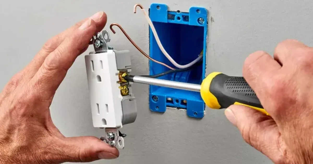 Electrician tightening a wall outlet with a screwdriver